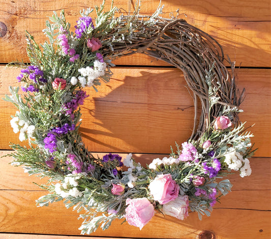 Create this DIY Spring Wreath that has fresh Juniper, Sage, purple and white Statice and pink preserved roses on a grapevine wreath base.